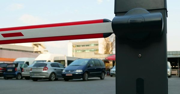 Heavy-duty parking barrier gate arm raised at a facility entrance with access control hardware