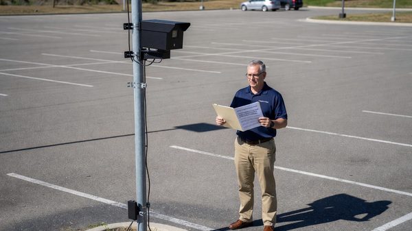 Compliance officer reviewing a data privacy policy document beside a license plate recognition camera installation